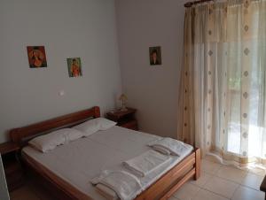 una camera da letto con un letto con lenzuola bianche e una finestra di Lefkas house with garden a Tsoukalades