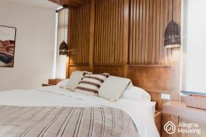 a bedroom with a bed with a wooden wall at 103 Arje Suites Campestre by Alegría Housing in Las Pilas