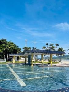 a bridge over a pool of water with palm trees at Apartamento aconchegante no Boqueirão in Santos