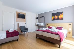 a bedroom with two beds and a chair at Hotel Montovani in Bruges