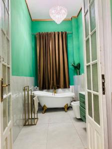 a bathroom with a tub and a green wall at LAYA Old City in Bucharest