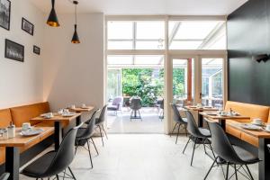 a restaurant with wooden tables and chairs and a large window at Hotel Montovani in Bruges