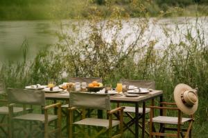 a table with chairs and food on it next to a river at Zambezi Sands by Batoka in Victoria Falls