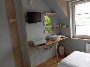 a small bathroom with a sink and a television at Le relais du Perche in Les Croix Chemins