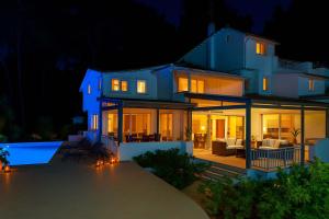 Una gran casa azul de noche con piscina. en Hera's Resort with Private Pool and Lush Garden, en Sani Beach