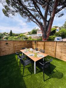 a wooden table and chairs on a lawn with a tree at Pinelodge Azure in Roquebrune-sur-Argens +8 photos