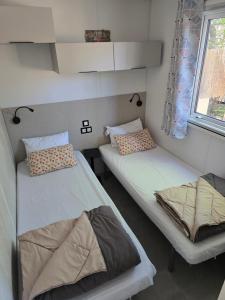 two twin beds in a room with a window at Mobil home 3 ch 6 pers Camping Mayotte in Biscarrosse +29 photos