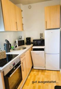 a kitchen with white appliances and wooden cabinets at Leuchtfeuer in Wendtorf
