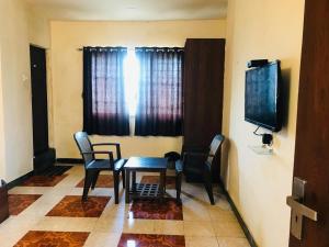 ein Esszimmer mit Tisch, Stühlen und Fernseher in der Unterkunft J J Lodging in Kolhapur