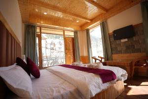 ein Schlafzimmer mit einem Bett und einem großen Fenster in der Unterkunft Wooden Castle Hotel and Resort in Manali