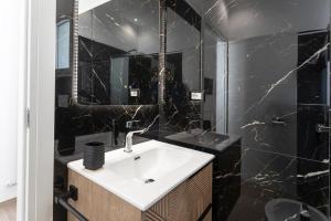 a bathroom with a white sink and black marble walls at ApartHotel Angelo - Salento Reservation in Racale +37 photos