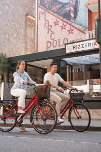 a man and a woman riding bikes down the street at Hotel Marco Polo in Lido di Jesolo
