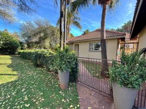a house with two large plants in front of a fence at Shamba Self-Catering in Pretoria