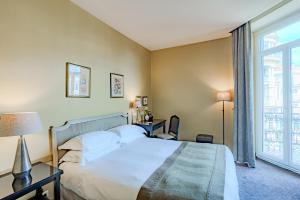 a bedroom with a bed and a large window at Le Cavendish in Cannes