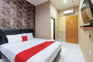 Un dormitorio con una cama con una manta roja encima. en Hotel Tiga-Er Syariah Karawang, en Karawang
