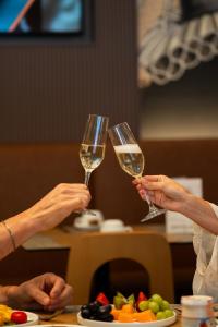 two people holding up glasses of white wine at Hotel Marco Polo in Lido di Jesolo