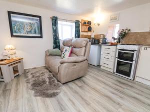 een woonkamer met een stoel en een keuken bij Wayside Farm Cart Cottage in Scarborough