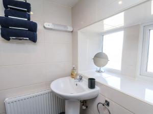 een witte badkamer met een wastafel en een spiegel bij Wayside Farm Cart Cottage in Scarborough +26 foto's
