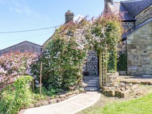 een tuin met een pergola bedekt met bloemen bij Wayside Farm Cart Cottage in Scarborough