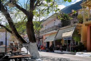 a street with a tree and tables and buildings at il vicolo studio in Ágios Matthaíos