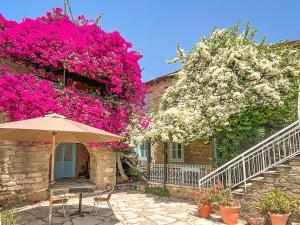 an umbrella sitting in front of a building with flowers at Cyprus Villages Hotel & Restaurant - Central Location - Bed & Breakfast - With Access To Pool And Stunning Views in Tochni