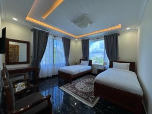 Un dormitorio con dos camas y un escritorio y un espejo. en Relax Inn Skardu, en Skardu