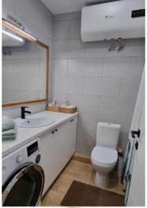 a bathroom with a toilet and a sink and a washing machine at New 2-Room Apartment near Sportivnaya Харьков, Тарасенка 92а in Dobrovelychkivka