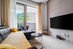uma sala de estar com um sofá e uma TV de tela plana em AURA TOWER Apartments by Gaby em Rafailovici