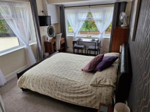 a bedroom with a bed and a table and windows at Greenlands Guest House in Highbridge