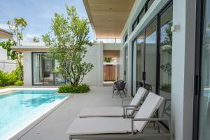 an outdoor patio with chairs and a swimming pool at Mouana Breeze Mai Khao 4-bedroom Pool Villa 9925 in Mai Khao Beach