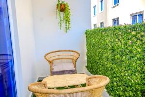 a wicker chair sitting on a balcony next to a green hedge at Coastal 3BR Vibe, GEM in Nyali in Mombasa