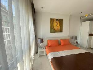 a bedroom with a bed with orange pillows and a painting at The Gallery Condominium M in Jomtien Beach +24 photos