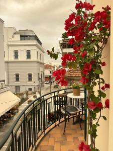a balcony with red flowers and a table and chairs at Borel apartment in Volos