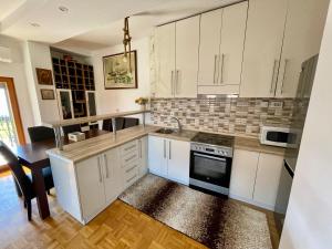 a kitchen with white cabinets and a sink and a table at MyHOME Apartment in Struga