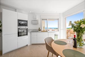 a kitchen with white cabinets and a table with flowers at Secret View Riviera Del Sol in Sitio de Calahonda