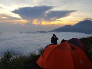 a man sitting on top of a mountain with tents at Above the Clouds Camp in Kintamani +9 photos