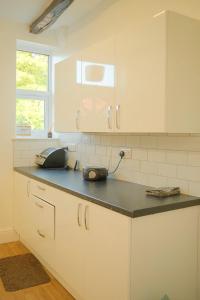a kitchen with white cabinets and a black counter top at 3 Bedroom House by Brookland Stays Serviced Accommodation Short Lets Leeds in Yeadon