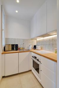 a white kitchen with white cabinets and appliances at Calm Square Flat in Boulogne-Billancourt +5 photos