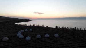 a group of white tents on the shore of a body of water at AiSun Eco Yurt Camp in Tossor