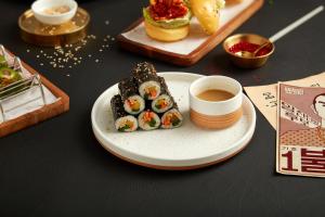 a plate of sushi and a cup of coffee on a table at Sindhorn Midtown Hotel Bangkok, Vignette Collection by IHG in Bangkok