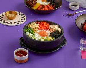 a table with a bowl of noodles and other foods at Sindhorn Midtown Hotel Bangkok, Vignette Collection by IHG in Bangkok