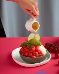 a person pouring honey onto a bowl of fruit at Sindhorn Midtown Hotel Bangkok, Vignette Collection by IHG in Bangkok
