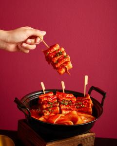 a person holding a piece of food in a pan at Sindhorn Midtown Hotel Bangkok, Vignette Collection by IHG in Bangkok