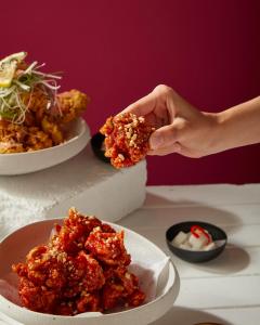 a person holding a piece of food over a plate of food at Sindhorn Midtown Hotel Bangkok, Vignette Collection by IHG in Bangkok