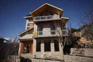 ein Haus mit zwei Stühlen davor in der Unterkunft Wooden Castle Hotel and Resort in Manali