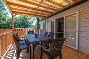 Un patio con una mesa y sillas en una terraza. en Camping 3 étoiles - Piscine - ccbbehi, en Verruyes