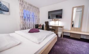 a bedroom with a bed and a desk and a mirror at Hotel Villa Sulmana in Neckarsulm