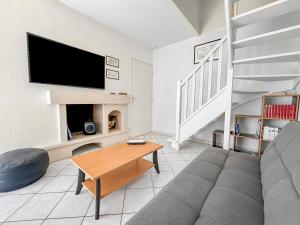 a living room with a couch and a tv at La Pause Cabourgeaise in Cabourg