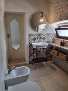 a bathroom with a sink and a toilet and a mirror at I Trulli di Nonna Maria in Alberobello