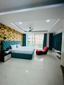 a bedroom with a large bed and a red chair at Hotel Elite Stay - Ashoka Nagar, Kharadi, Pune in Pune